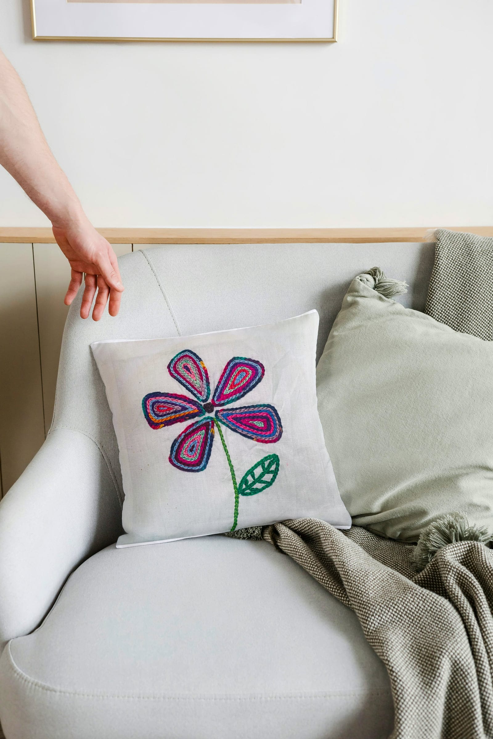 Hand holding a flower-embroidered cushion