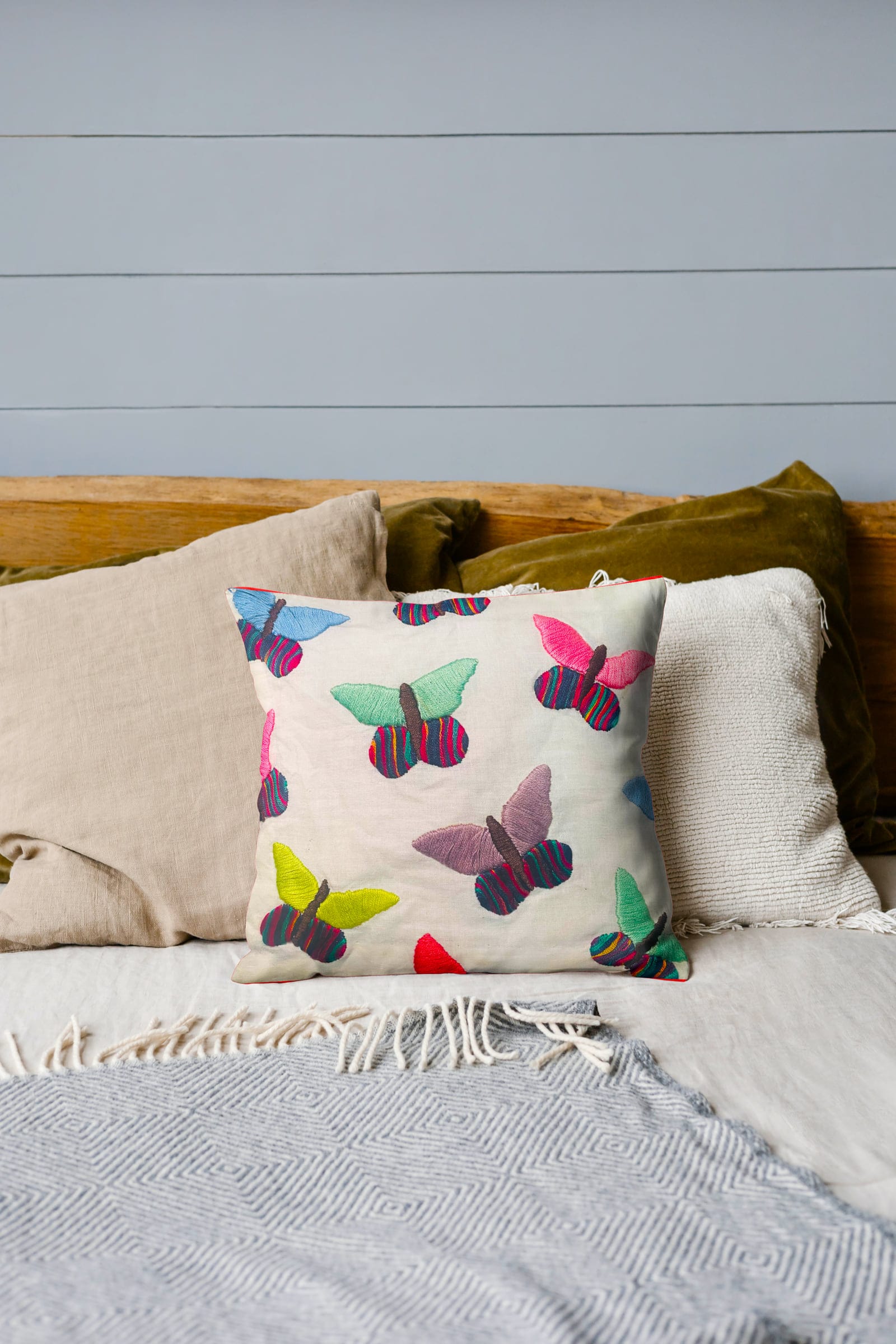 Butterfly-embroidered cushion styled on a bed