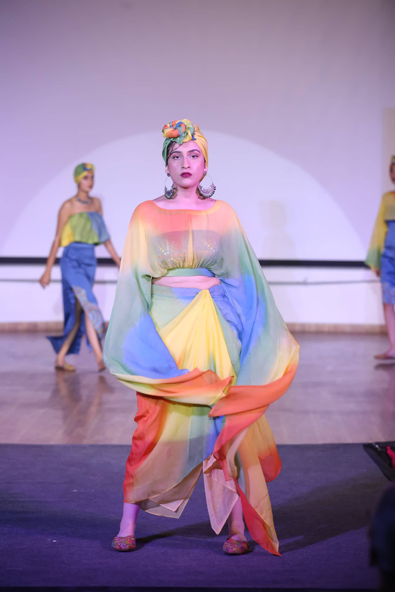 Model on the runway in a rainbow-dyed cape from the Tribal Threads collection